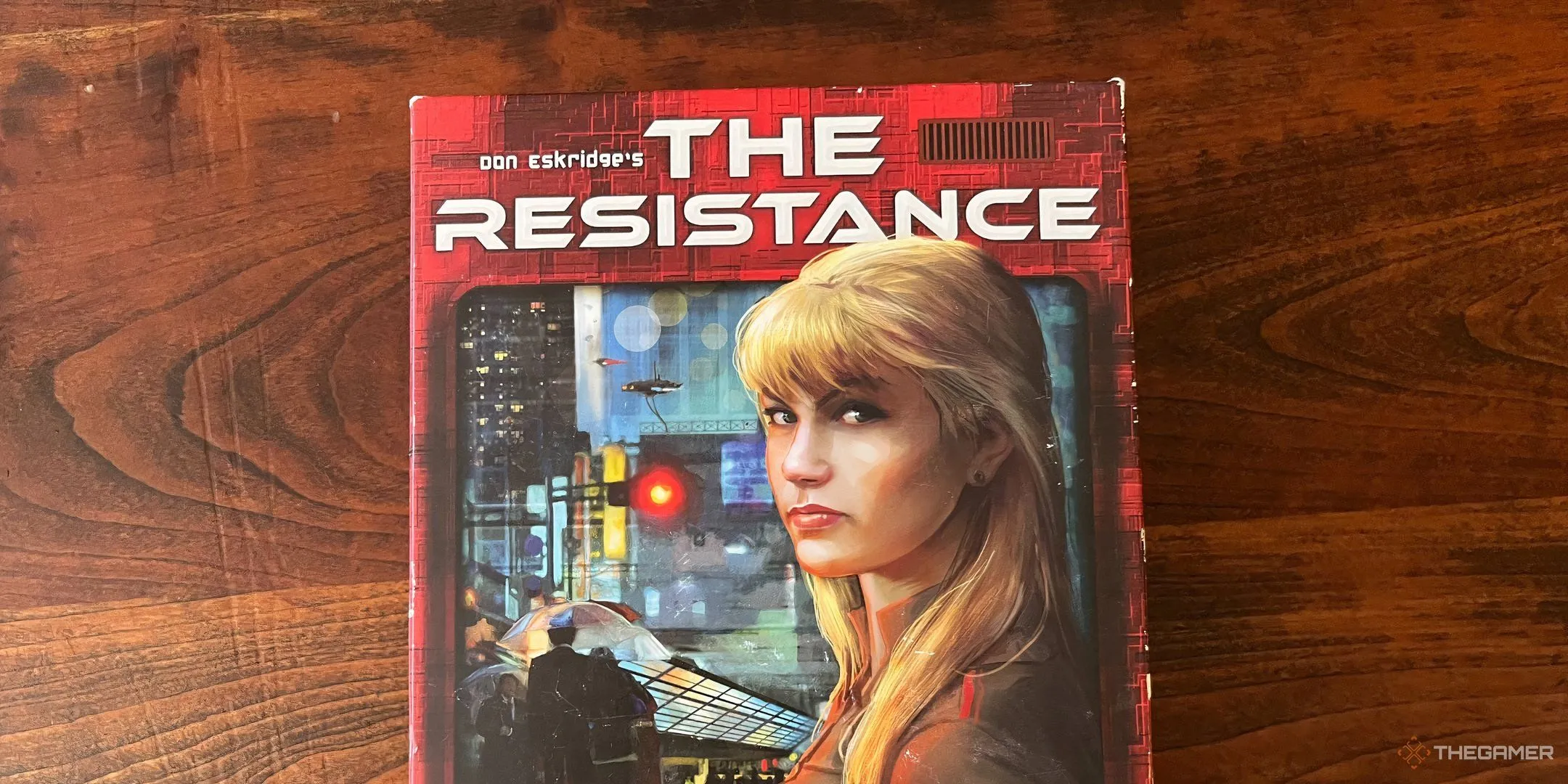 Bìa hộp game The Resistance với hình ảnh nữ điệp viên tóc vàng bí ẩn, biểu tượng cho trò chơi phản bội và liên minh.