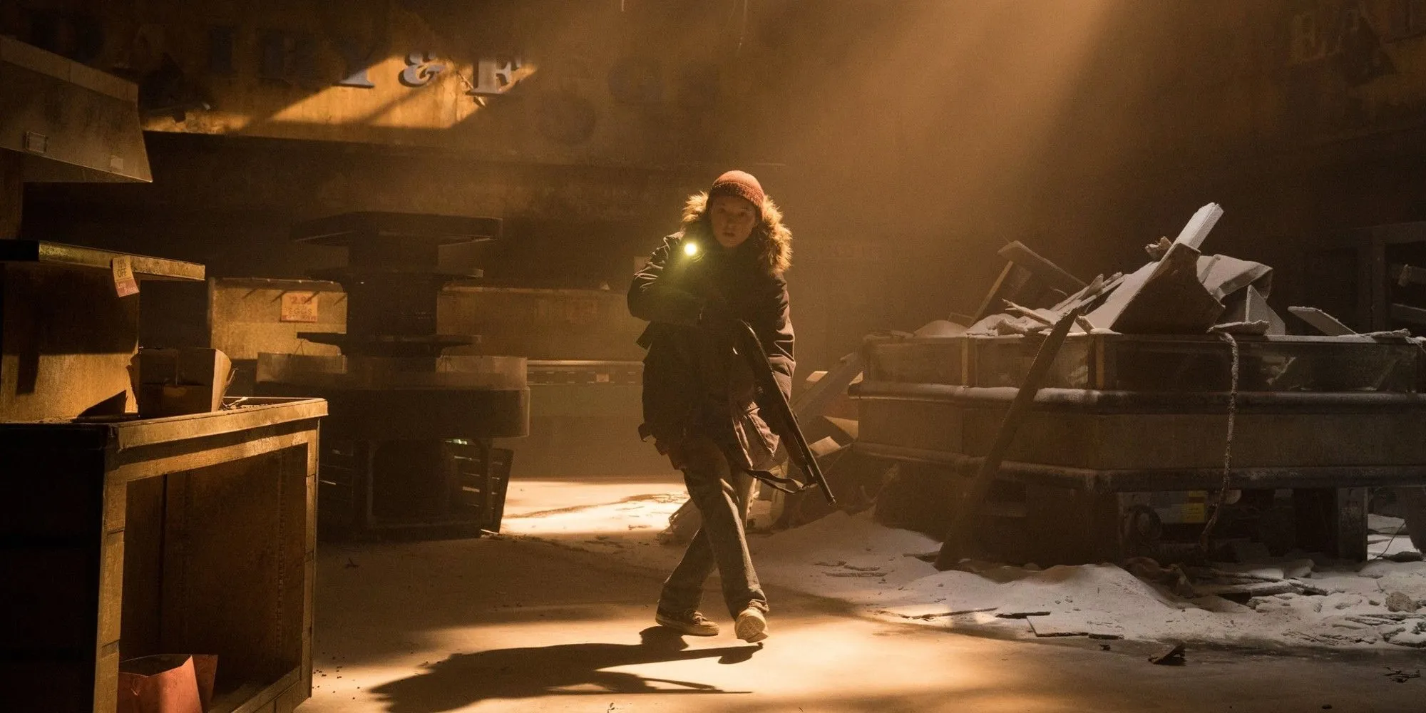 Ellie (Bella Ramsey) thận trọng khám phá một khu vực đổ nát trong The Last of Us mùa 2, mang theo vũ khí.