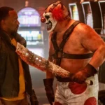 Sweet Tooth kề mã tấu đẫm máu vào cổ John Doe trong series Twisted Metal
